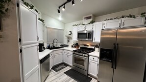 A modern kitchen with white cabinets, stainless steel appliances, and a black countertop.