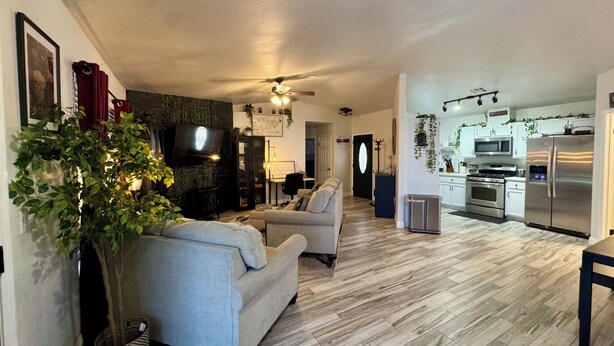 A living room with a sofa, a TV, and a ceiling fan.