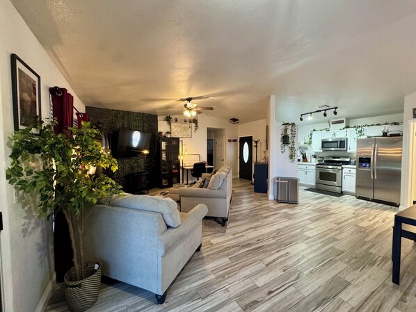 A living room with a sofa, a TV, and a ceiling fan. - Lovely, Peaceful, and Modern Las Vegas Home! Close to Strip! (North Las Vegas)