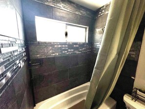 Een badkamer met een bad, een raam en een douchegordijn.