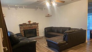 A living room with a fireplace, two leather sofas, and a ceiling fan.