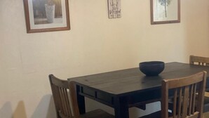 A dining table with chairs, a bowl, and framed pictures on the wall.