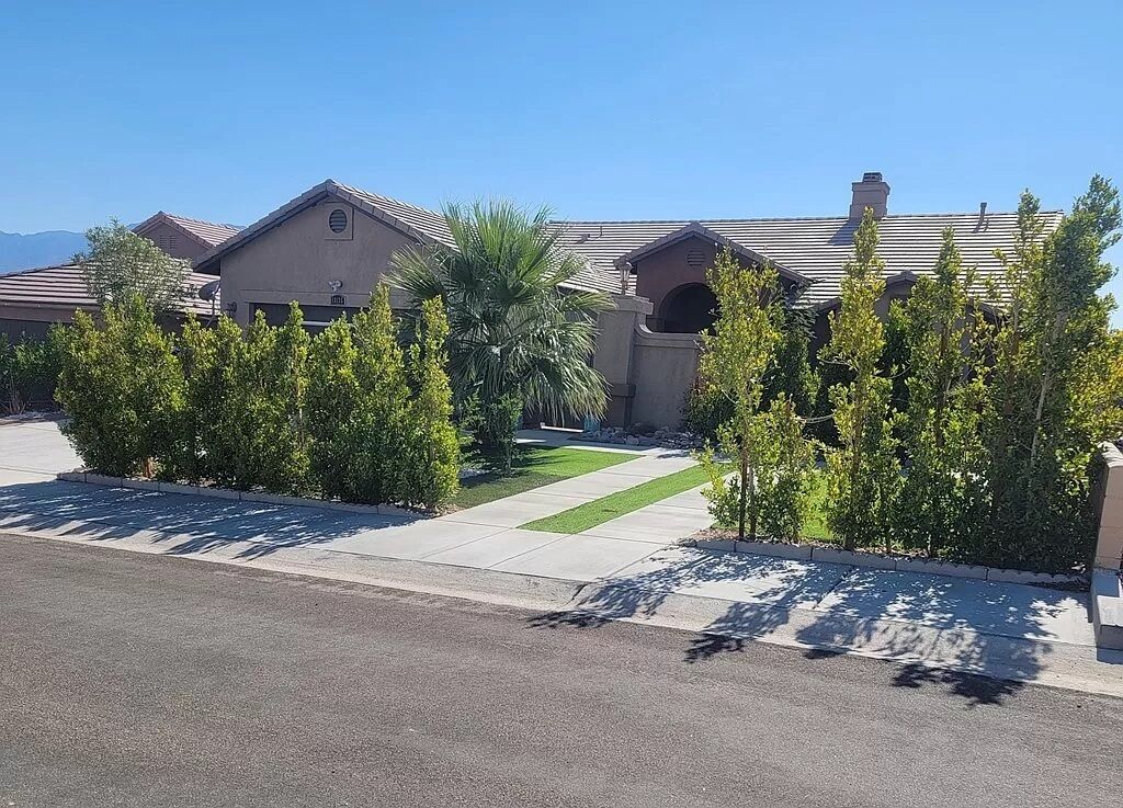 A residential area with houses, a well-maintained lawn, and a clear sky.