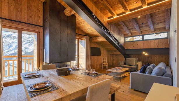 Ein Holzinterieur mit einem für zwei Personen gedeckten Esstisch, einer Couch und einer Treppe.