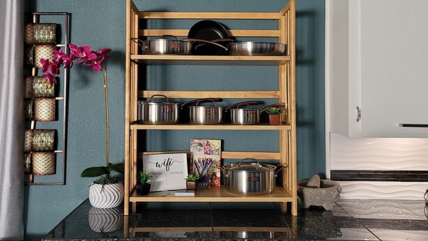 A kitchen with a wooden shelf holding pots and pans, a wall clock, and a potted plant. - No closer lodging to Crystal Bridges exists! (Bentonville)