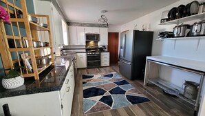 A modern kitchen with white cabinets, stainless steel appliances, and a patterned rug. - No closer lodging to Crystal Bridges exists! (Bentonville)