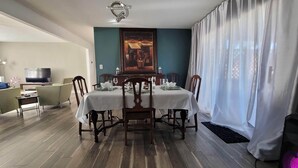 A dining area with a table set for four, a television in the background, and a painting on the wall. - No closer lodging to Crystal Bridges exists! (Bentonville)