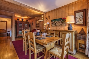 Ein Esszimmer aus Holz mit einem großen Tisch, gedeckt für sechs Personen, umgeben von Stühlen.