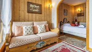 A cozy room with a wooden sofa, a bed, and a decorative archway. - Duplex Aiguille du midi large terrasse, Chamonix, France (Chamonix)