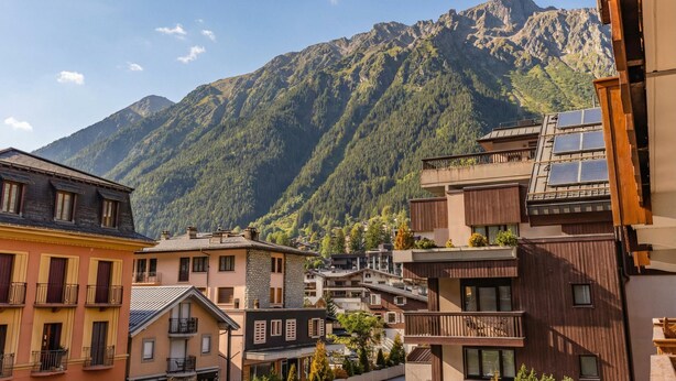A mountain town with buildings, some with balconies, and a mountain in the background. - Duplex Aiguille du midi large terrasse, Chamonix, France (Chamonix)