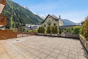 Ein Innenhof mit gefliestem Boden, einem Holzzaun und einem Gebäude mit einem Balkon.