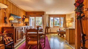 A wooden interior with a dining table, chairs, a red rug, and a view of the outside. - Duplex Aiguille du midi large terrasse, Chamonix, France (Chamonix)
