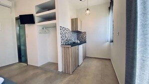 Una cucina compatta con zoccolo in piastrelle, forno integrato e lampada a sospensione.