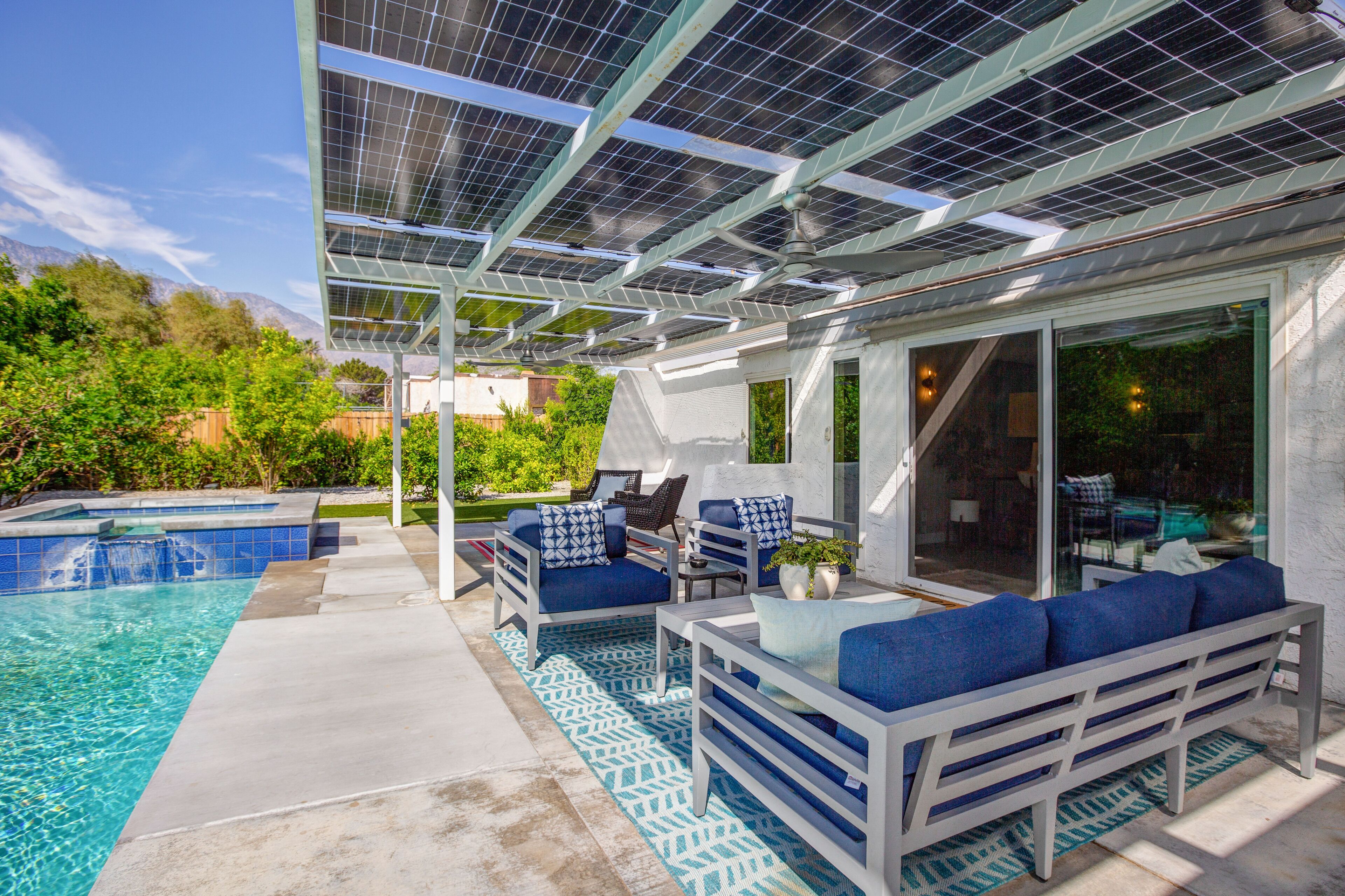 A poolside area with a covered seating area, a small waterfall feature, and a glass door leading to a patio.