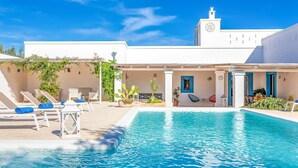 A pool area with lounge chairs and a small garden.