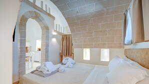A bedroom with a brick ceiling, an arched doorway, a bed with white linens, and a view of a bathroom. - Villa in Ostuni with 1 bedrooms sleeps 2 (Ostuni)