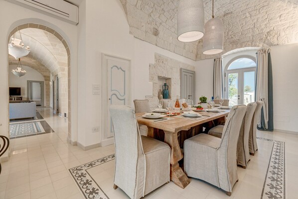 A dining area with a wooden table set for four, surrounded by upholstered chairs.
