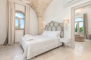 A modern bedroom with a large bed, a bedside table, and a view of the outdoors through a window.