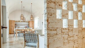A spacious kitchen with a dining area, featuring a modern chandelier, wooden cabinets, and a stone wall. - Villa in Ostuni with 6 bedrooms sleeps 11 (Ostuni)