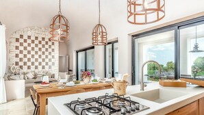 A modern kitchen with a gas stove, wooden cabinets, and a large window offering a view of the outdoors. - Villa in Ostuni with 6 bedrooms sleeps 11 (Ostuni)