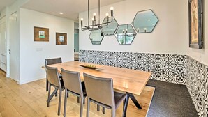 A modern dining area with a wooden table, metal chairs, and a geometric wall decoration.