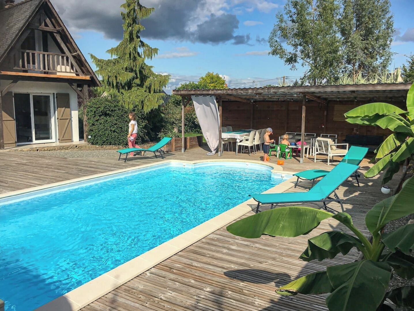 Ein Schwimmbad mit Liegestühlen und einer überdachten Sitzgelegenheit.