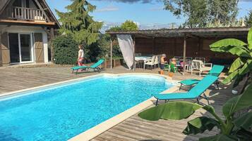 Una piscina con sillas de descanso y una zona de estar techada.