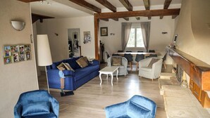 En rummelig opholdsstue med blå sofa, to blå lænestole, et hvidt sofabord og pejs.