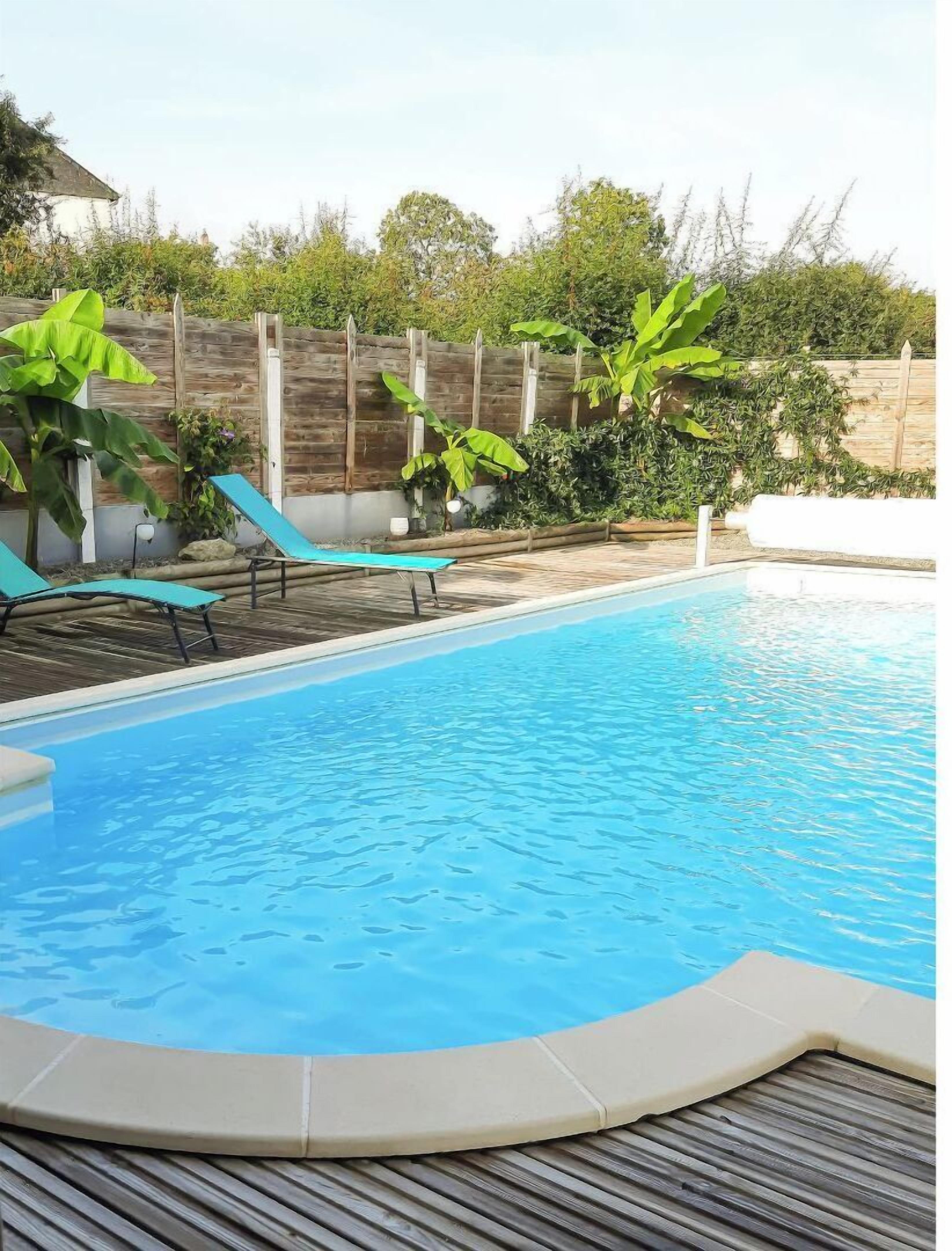 A swimming pool with lounge chairs and a wooden deck.