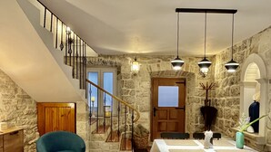 Un comedor con pared de piedra, escalera de madera y mesa lista para comer.