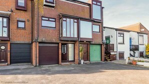 A two-story brick building with a garage door, a green door, and a small balcony. - Rampart View -  a house that sleeps 6 guests  in 3 bedrooms (Gosport)