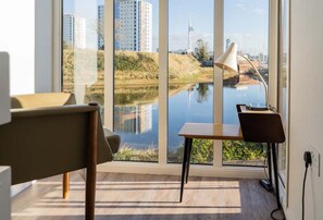 A modern room with a large window offering a view of a body of water and buildings. There is a desk with a chair and a lamp. - Rampart View -  a house that sleeps 6 guests  in 3 bedrooms (Gosport)