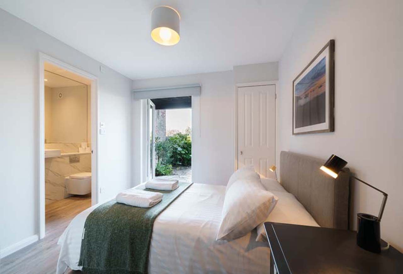 Une chambre à coucher moderne avec un lit, des tables de chevet, une commode, une lampe et une fenêtre.
