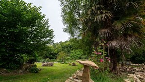 Un jardin avec un sentier en pierre, une végétation luxuriante et un palmier.