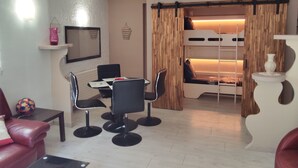 Une pièce de taille modeste comprenant un lit superposé, une table à manger avec des chaises, un petit canapé et une table basse.