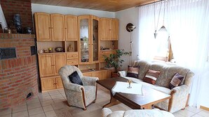 Una sala de estar con chimenea, armarios de madera, un sofá, sillones y una mesa de centro.