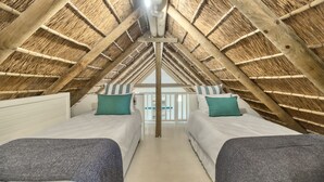 A room with two beds, a wooden ceiling, and a view through a glass door.