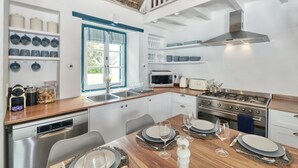 A modern kitchen with white cabinets, a wooden countertop, and a dining area set for four.
