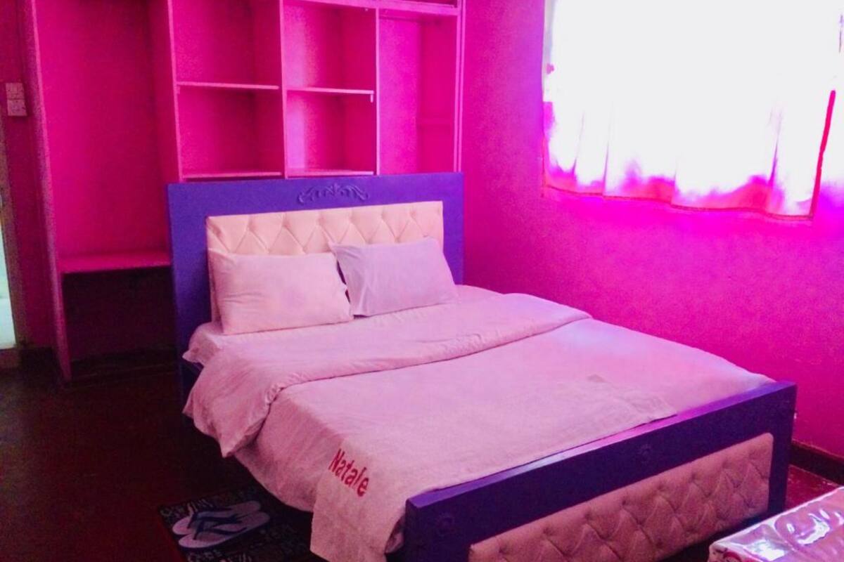 A bedroom with a bed, a nightstand, and a window with curtains.