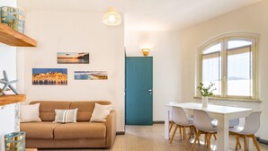 Ein modernes Wohnzimmer mit Sofa, Esstisch, Stühlen und Bildern an der Wand.