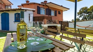 Eine Terrasse mit Tisch, gedeckt für eine Mahlzeit, einer Weinflasche und Gläsern.