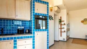 Eine Küche mit blauen Fliesen, Holzschränken, einer Mikrowelle und einer Kaffeemaschine.