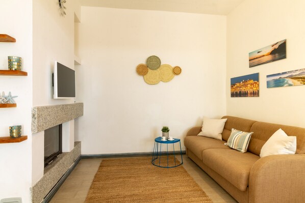 Una sala de estar con chimenea, un sofá, una mesa de centro y decoración en la pared.