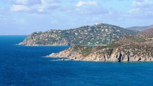Un paysage côtier avec un village perché sur une colline, une côte rocheuse et une mer bleue et limpide.