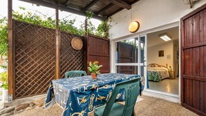 Un patio couvert avec une table dressée pour les repas, une chaise et une plante en pot.