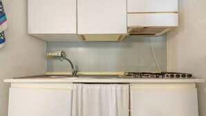 Une petite cuisine équipée d’un évier, d’une cuisinière et d’une serviette accrochée à la porte.