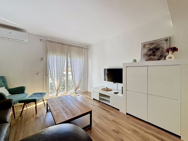 A modern living room with a wooden floor, a sofa, a coffee table, a TV, and a cabinet.