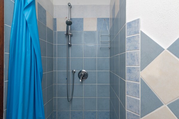 Ducha con cabezal de ducha de mano y mandos en la pared.