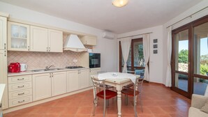A kitchen with a dining table, chairs, and a view through a glass door.