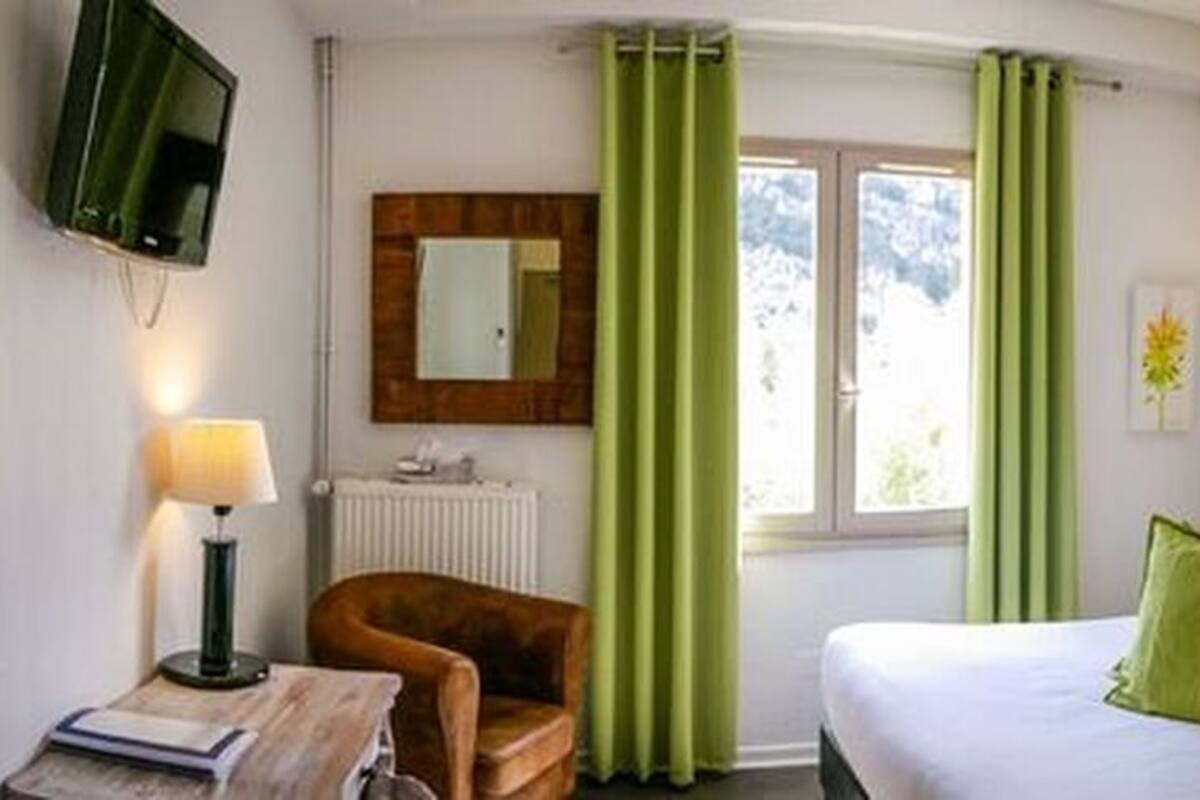 Une chambre d’hôtel avec deux lits, une télévision, un miroir, une lampe et une fenêtre avec des rideaux.
